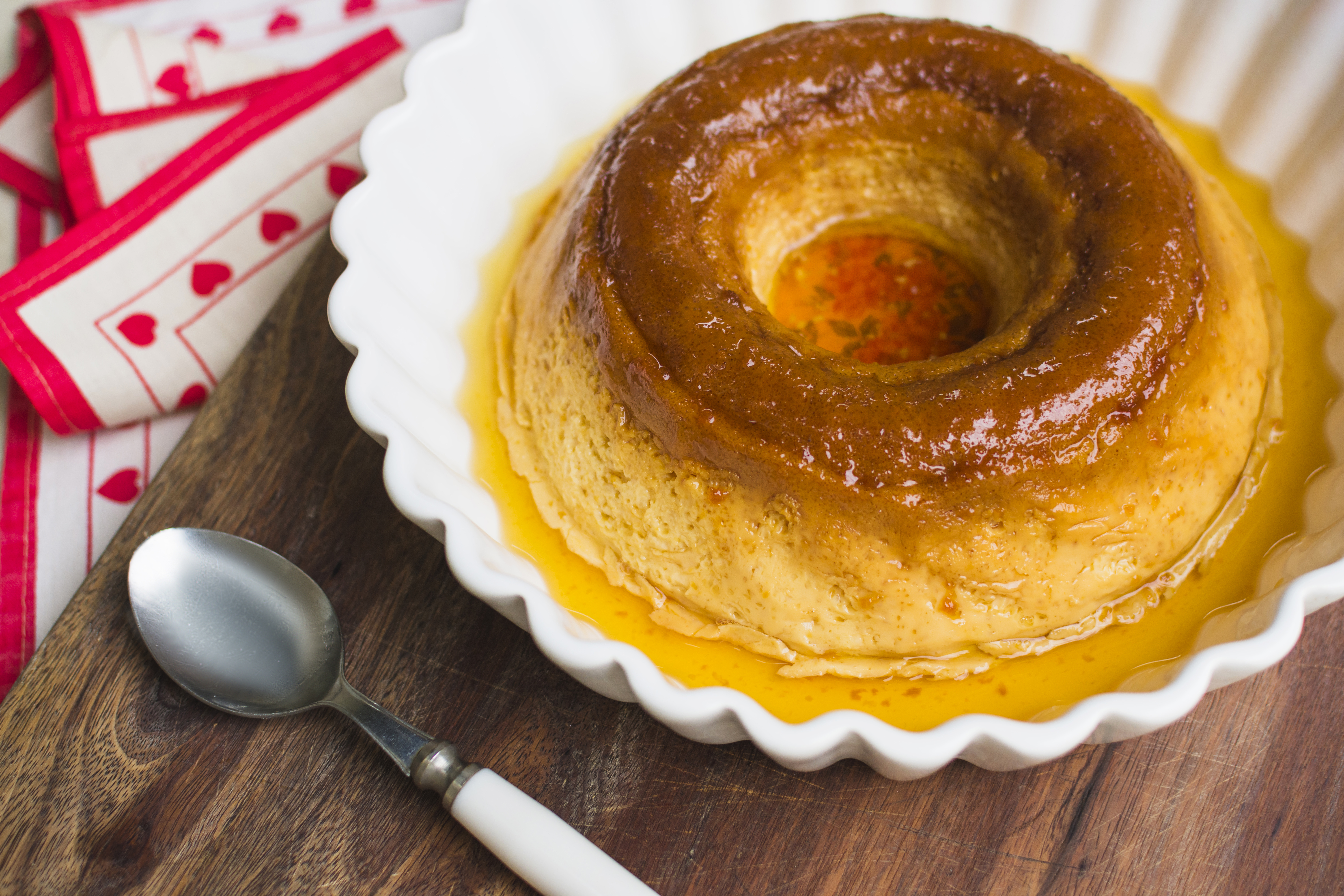 A spoon along side a pudding on a plate