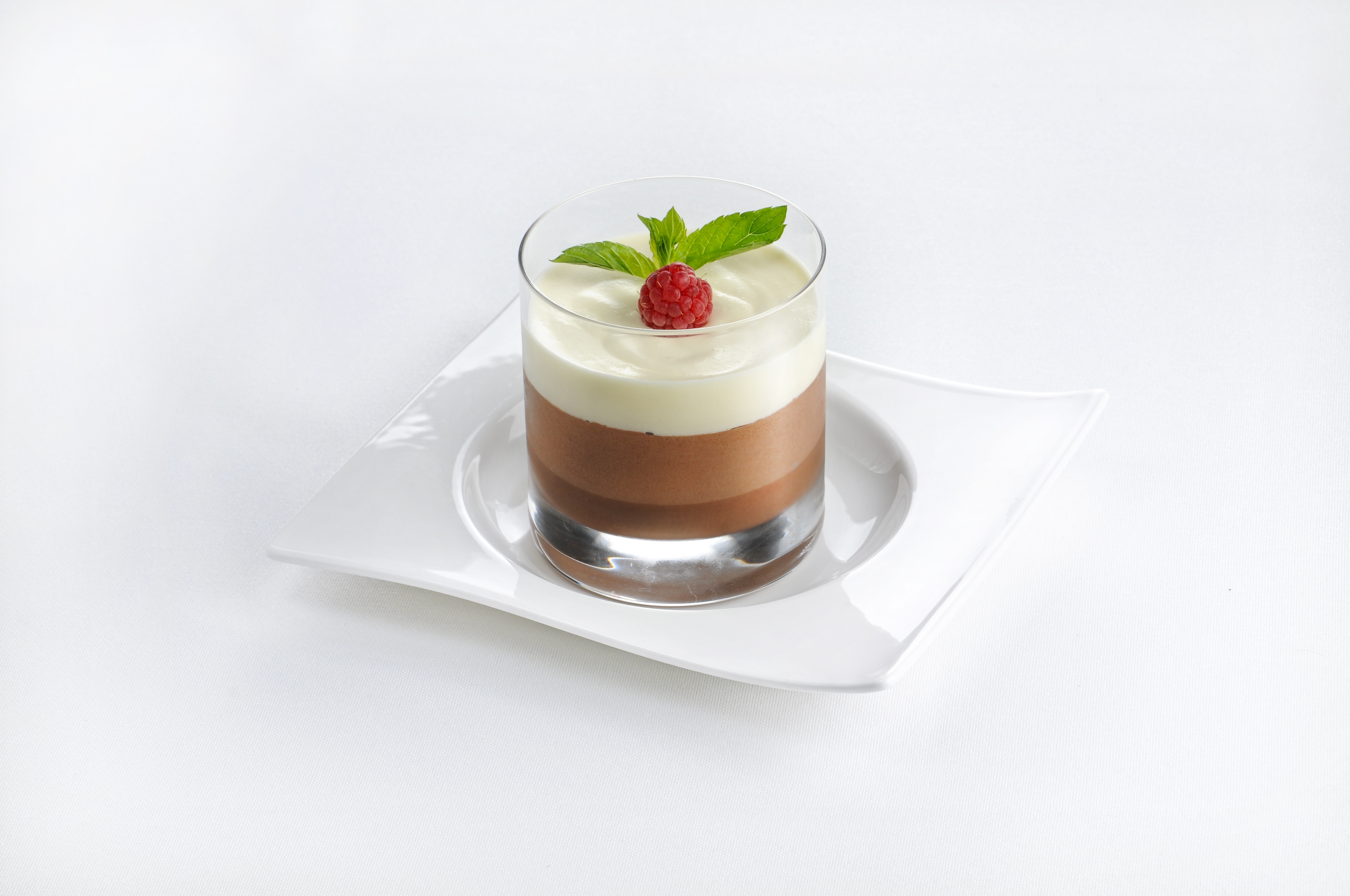 A glass over a plate with a chocolate mousse in it